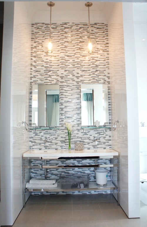 This polished nickel double vanity fit perfectly in this space!  The reflective White Ice walls, horizontal staggered glass and marble tile, and polished metal all twinkle from the lights of the two fabulous "Caviar" pendants by Arteriors.  The mirror/shelves are by Waterworks.